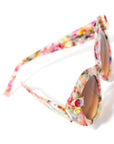 top view of multi-coloured sunglasses with gemstone embellishments on the frame corners, with a brown gradient lense, set against a white background