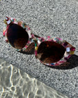 colourful framed sunglasses are placed on a textured stone ledge, highlighting their bright hues