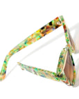 Colorful cat-eye sunglasses with a translucent multicolored frame and gradient brown lenses, featuring a stylish design and the brand name "MAUDE" on the side.