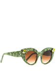 Side view of stunning cat eye sunglasses crafted with a green pearlescent look, featuring gemstone embellishments on the upper corners of the frame and a brown gradient lense. Set against a white backdrop