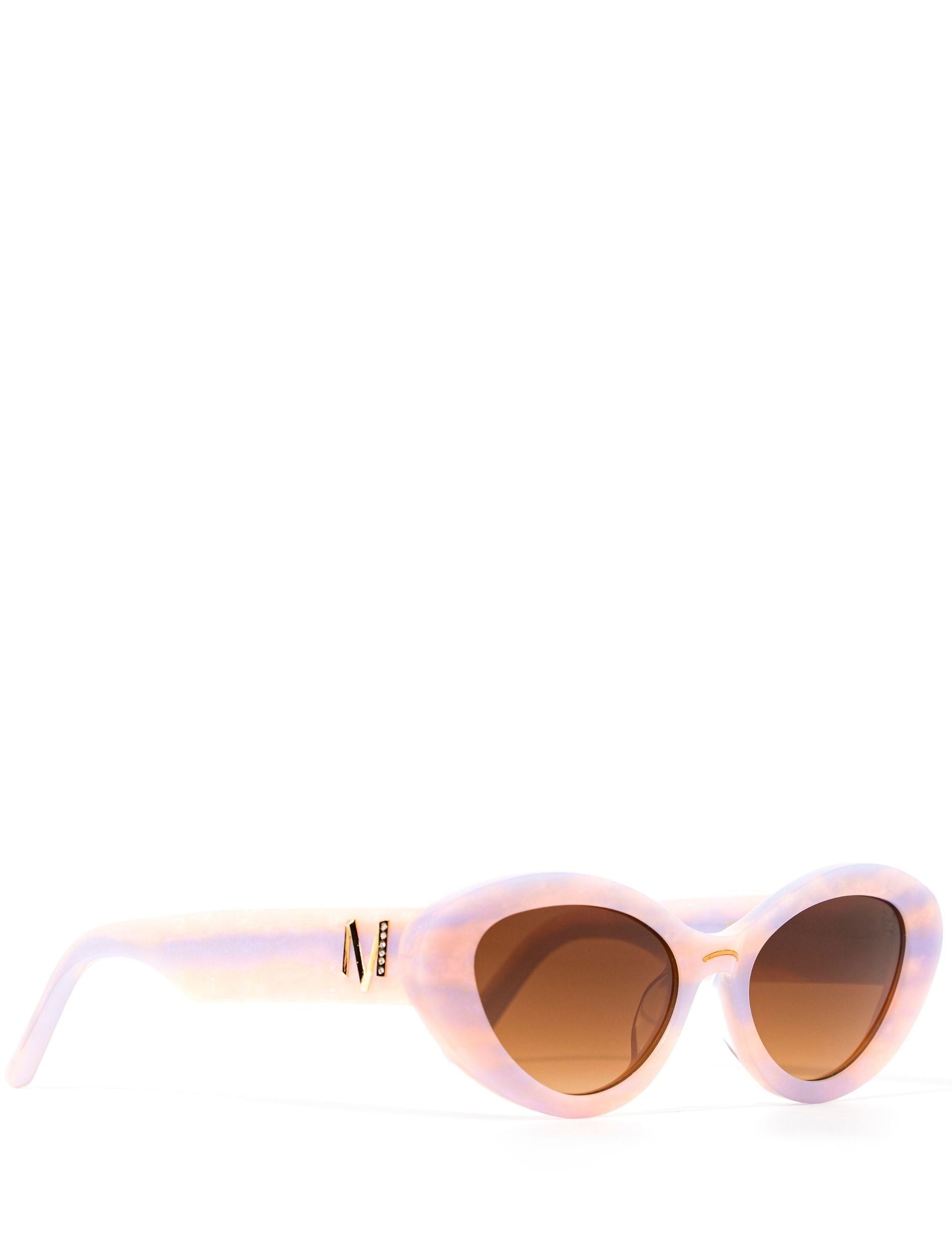 Side view of stylish pair of pastel pink and lilac sunglasses with a brown gradient lense set against a white background. there is a gold 'M' on the arm of the frame.