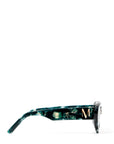 side view of a pair of stylish sunglasses in a green tortoise shell style displaced against a white back drop. You can see an embellished 'M' on the side of the frame arm