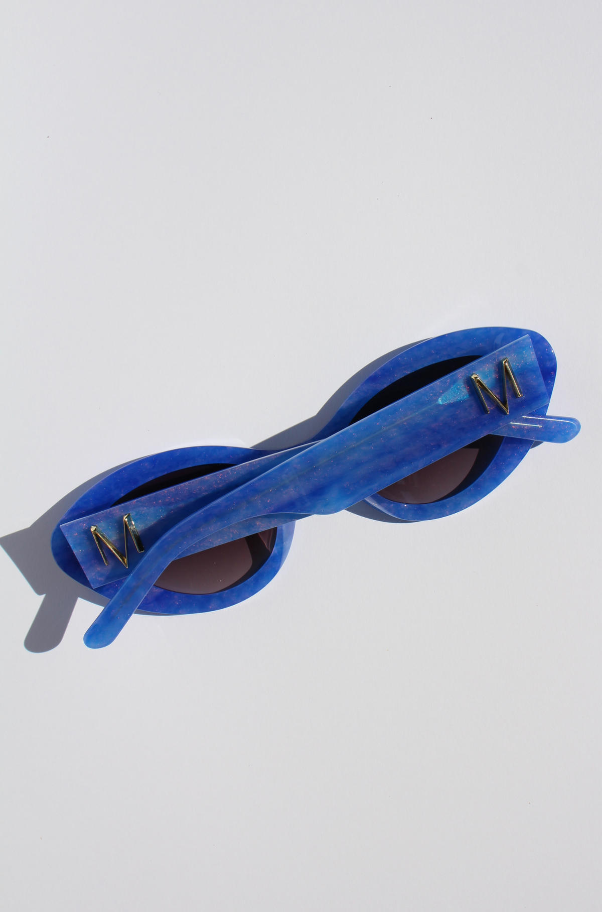 AZURIA ~ Oval shaped sunglasses in a luminous imperial blue with pink shimmer