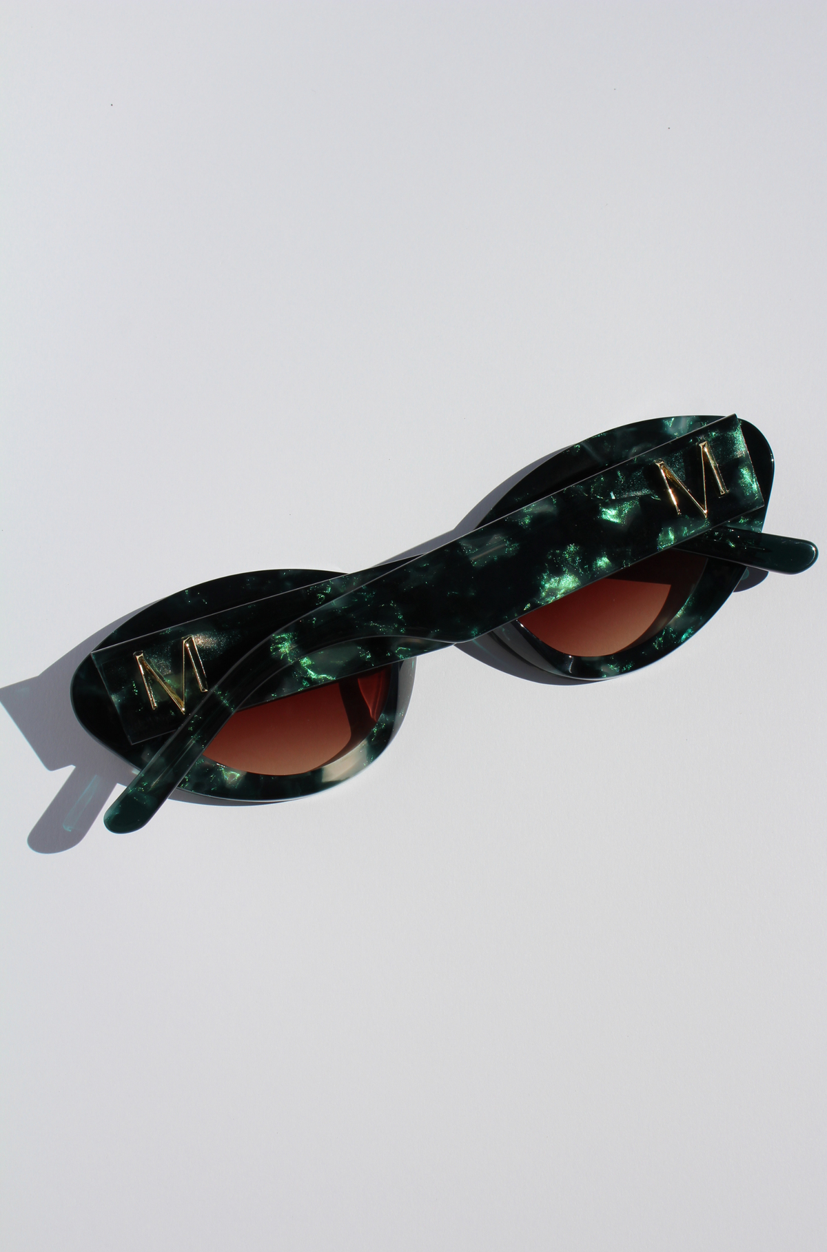 GLOWELLA ~ Oval shaped sunglasses in dark green with shimmering emerald tort
