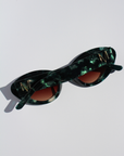 GLOWELLA ~ Oval shaped sunglasses in dark green with shimmering emerald tort