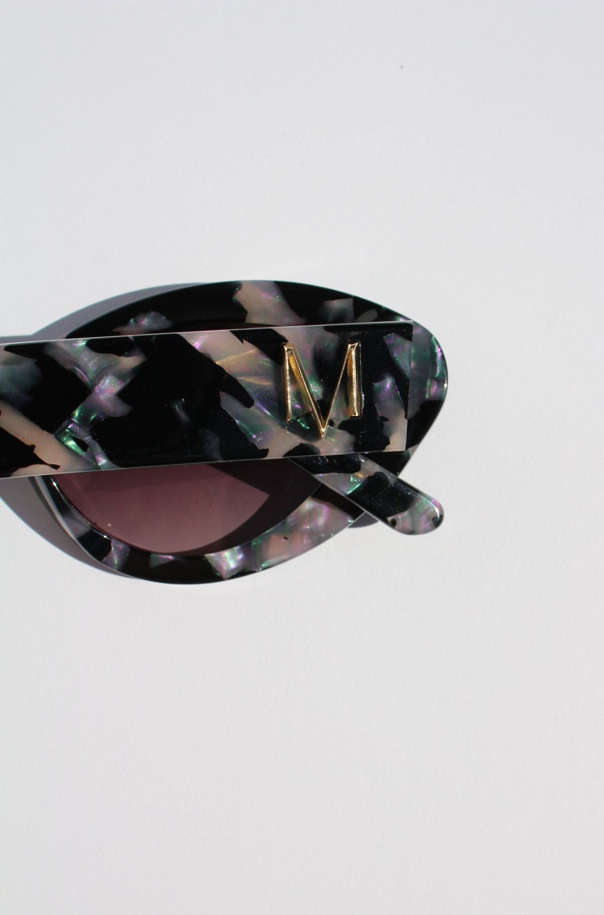ONYX NOIR ~ Oval shaped sunglasses in marbled black and blush with shimmering turquoise acetate