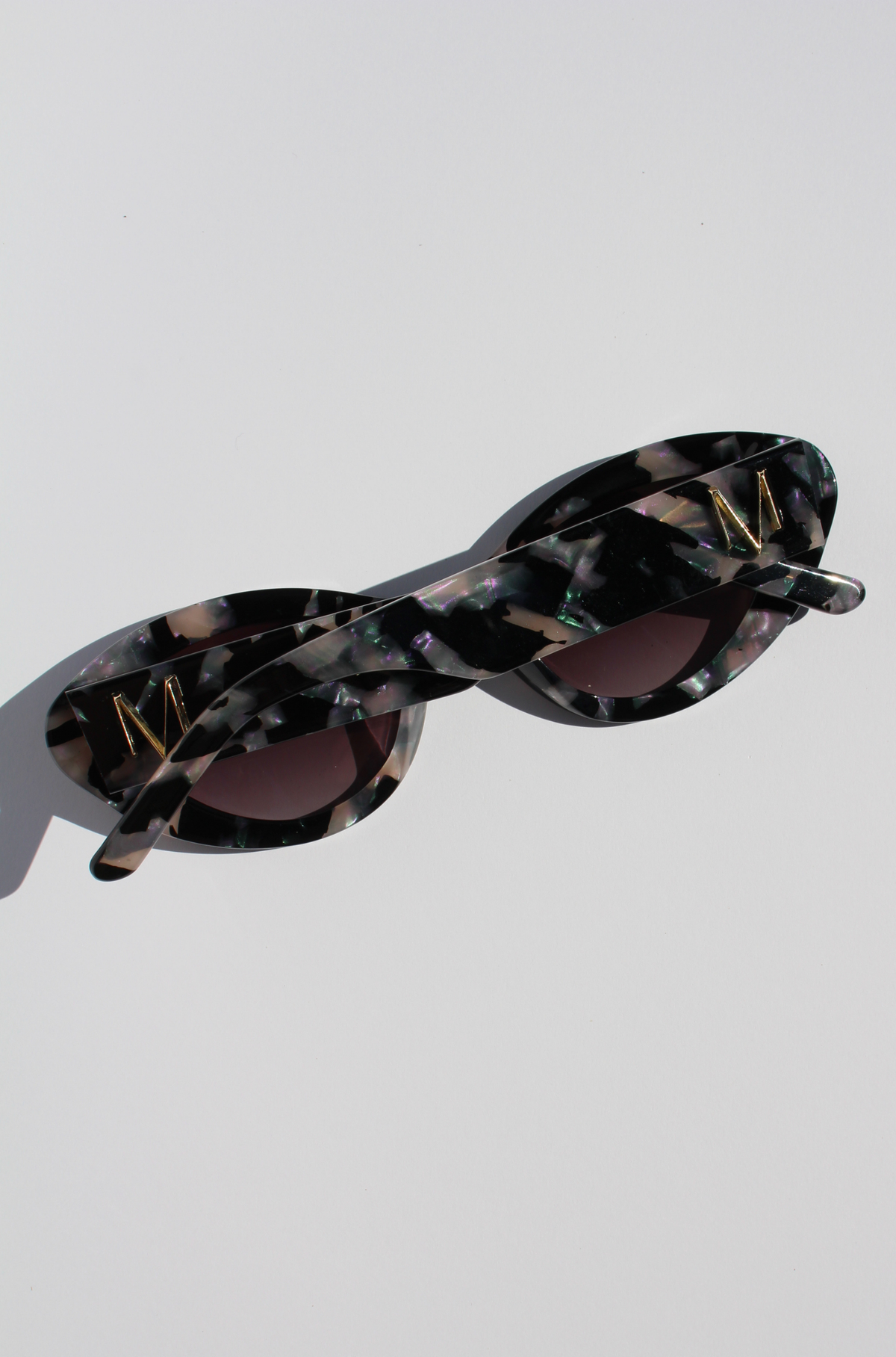 ONYX NOIR ~ Oval shaped sunglasses in marbled black and blush with shimmering turquoise acetate