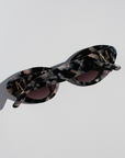 ONYX NOIR ~ Oval shaped sunglasses in marbled black and blush with shimmering turquoise acetate