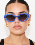 AZURIA ~ Oval shaped sunglasses in a luminous imperial blue with pink shimmer