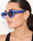 AZURIA ~ Oval shaped sunglasses in a luminous imperial blue with pink shimmer