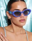AZURIA ~ Oval shaped sunglasses in a luminous imperial blue with pink shimmer