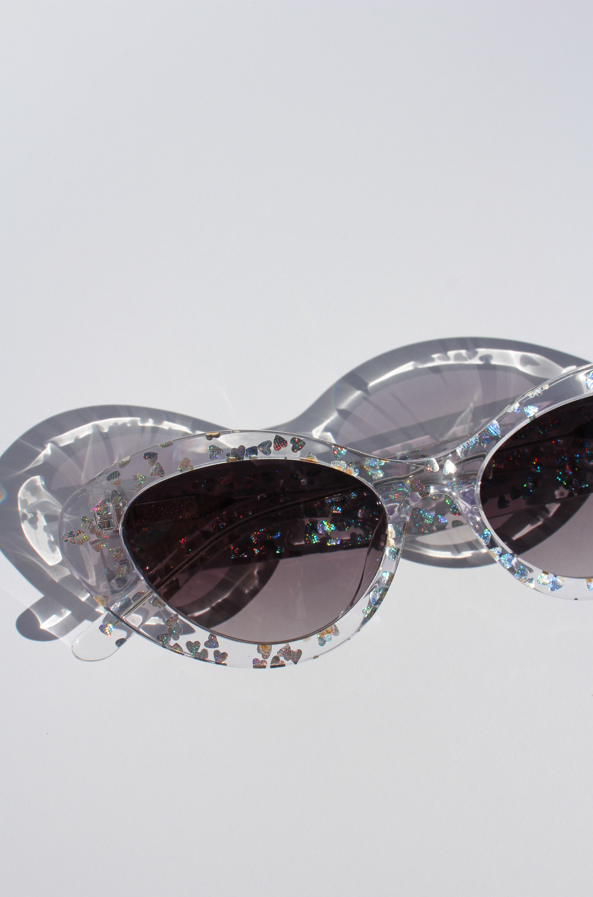 SILVELLE ~ Oval shaped sunglasses in clear acetate sprinkled with iridescent silver love heart sequins