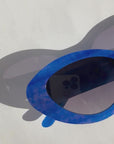AZURIA ~ Oval shaped sunglasses in a luminous imperial blue with pink shimmer